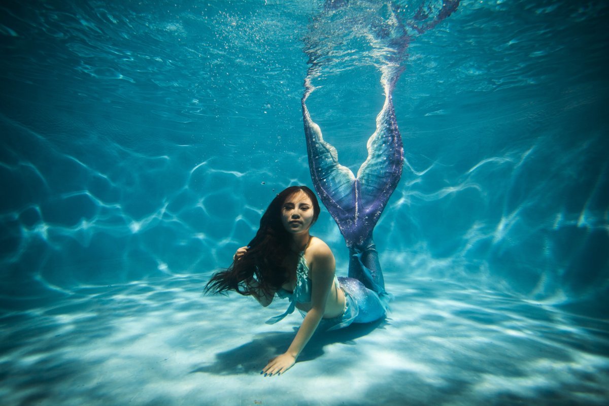 This photo taken on July 26, 2015 shows a woman clad in her self-made mermaid costume swimming in a pool in China's southwest Chongqing municipality.         