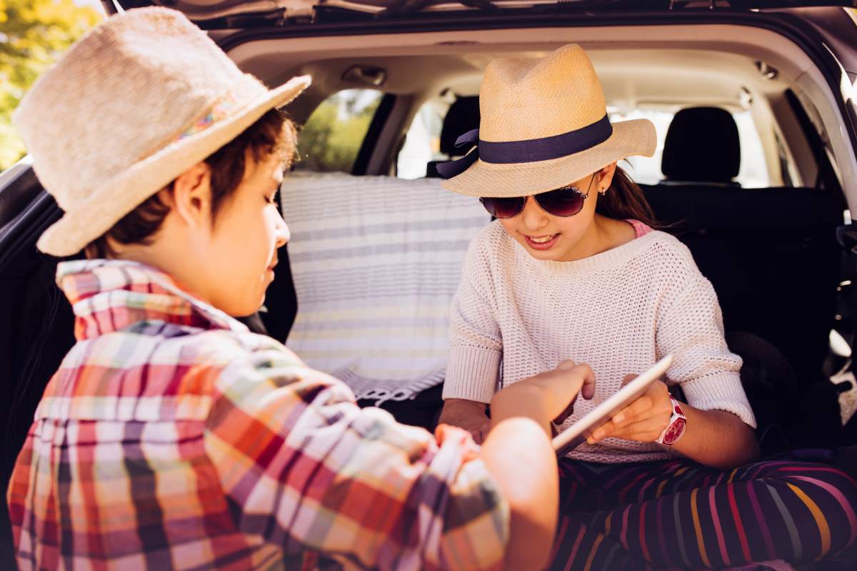Kids sitting in the car and playing with touchpad.