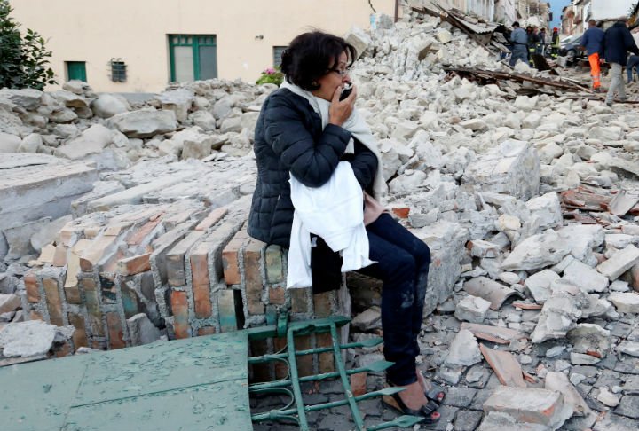 A woman sits amongst rubble following a quake in Amatrice, centra.