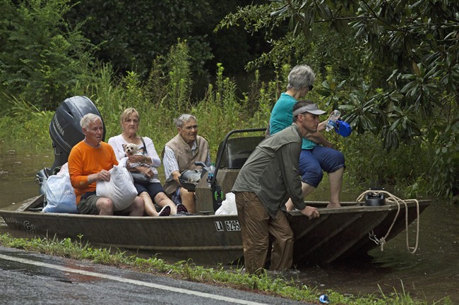 People arrive an area, to be evacuated by members of the Louisiana Army National Guard near Walker, La., after heavy rains inundated the region, Sunday, Aug. 14, 2016.