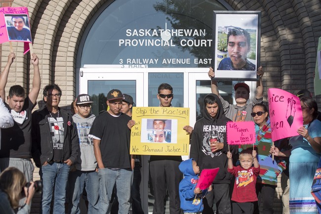 Family, friends and supporters for Colten Boushie hold signs during a rally outside of the Saskatchewan Provincial Court in North Battleford,Thursday, August 18, 2016. THE CANADIAN PRESS/Liam Richards