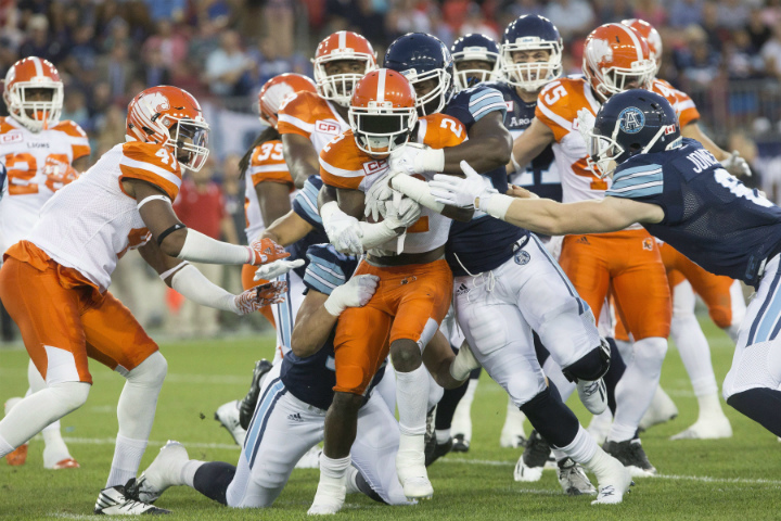 BC Lions' Chris Rainey (2) is swarmed as he tries to carry the ball through the Toronto Argonauts' defence during first half CFL football action, in Toronto on Wednesday, August 31, 2016. 