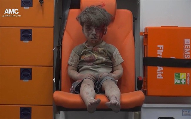 In this frame grab taken from video provided by the Syrian anti-government activist group Aleppo Media Center (AMC), a child sits in an ambulance after being pulled out or a building hit by an airstirke, in Aleppo, Syria, Wednesday, Aug. 17, 2016. 