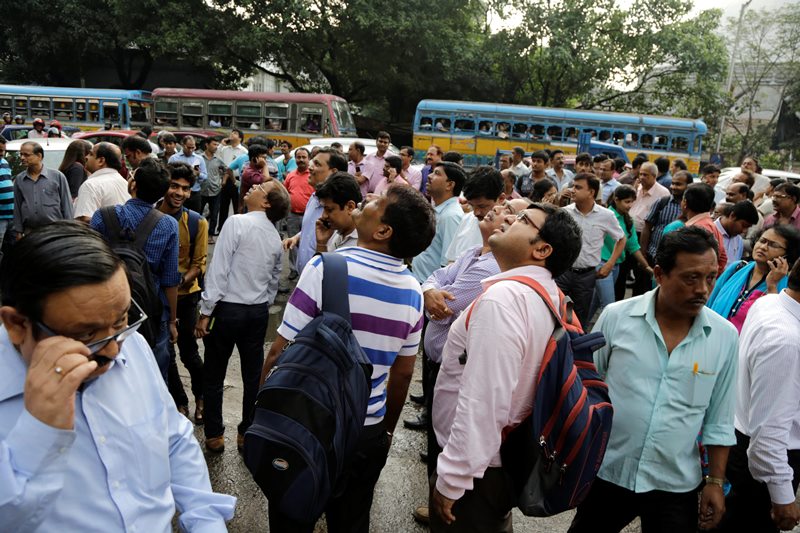 People stand in the street after they rushed out of their offices following tremors in Kolkata, India, Wednesday, Aug. 24, 2016. 