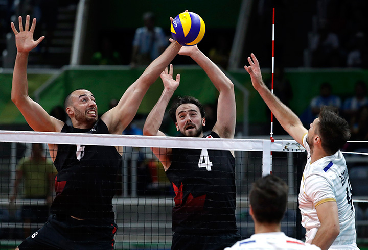 Canada's Justin Duff, left, blocks a spike from France's Antonin Rouzier, right, as teammate Nicholas Hoag watches during a men's preliminary volleyball match at the 2016 Summer Olympics in Rio de Janeiro, Brazil, Thursday, Aug. 11, 2016. 