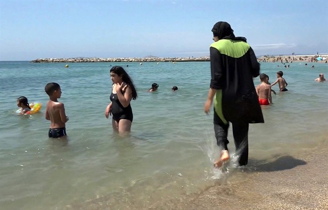 In this Aug.4 2016 file photo made from video, Nissrine Samali, 20, gets into the sea wearing a burkini, a wetsuit-like garment that also covers the head, in Marseille, southern France.
