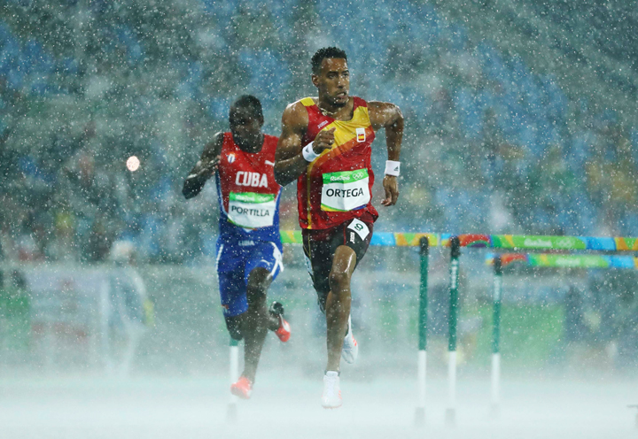 Jhoanis Portilla (CUB) of Cuba and Orlando Ortega (ESP) of Spain compete in the rain.