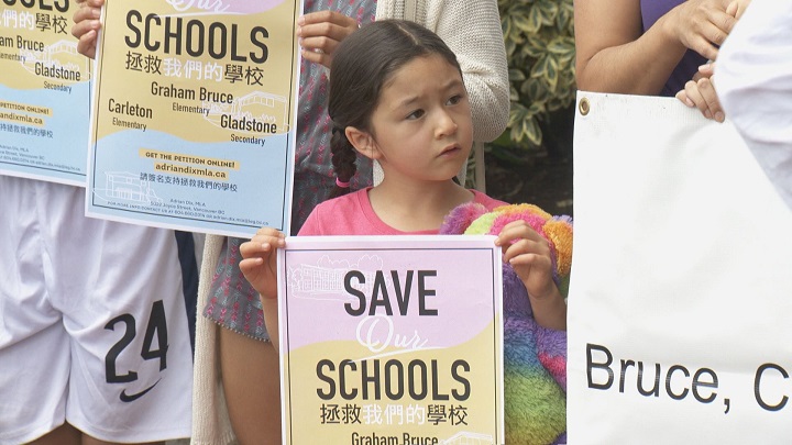 A young student looks on at a rally to save three schools in east Vancouver on August 4, 2016.