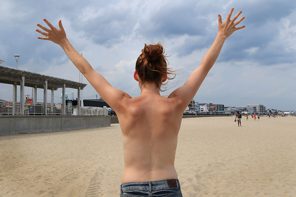 In this July 30, 2015 photo, Kia Sinclair, stands topless on Hampton Beach in Hampton, N.H. The New Hampshire movement, known as Free the Nipple, that sparked controversy when several legislators criticized its members is planning to return to the spotlight Aug. 28, 2016 when they celebrate GoTopless Day on some of the state's beaches. 