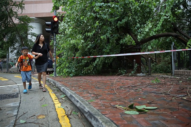 People walk past tree branches broken by strong winds caused by Typhoon Nida in Hong Kong, Tuesday, Aug. 2, 2016. The Hong Kong Observatory issued the number 8 storm signal as Typhoon Nida moves northwest across southern China, bringing high winds and heavy rain but no immediate reports of deaths or destruction. (AP Photo/Kin Cheung).