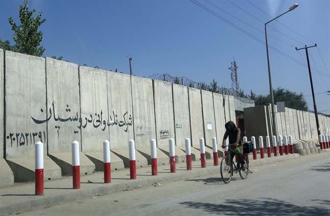An Afghan man pedals his bicycle past American University of Afghanistan in Kabul, Afghanistan, Monday, Aug. 8, 2016. Five gunmen wearing Afghan military uniforms abducted an American and an Australian in Kabul, a security official said Monday. Sediq Sediqqi, spokesman for the Afghan Interior Ministry, said that the two foreigners were taken from their SUV while driving on Sunday night on a main road near the university. They are believed to be employees of the university, he said. (AP Photo/Rahmat Gul).