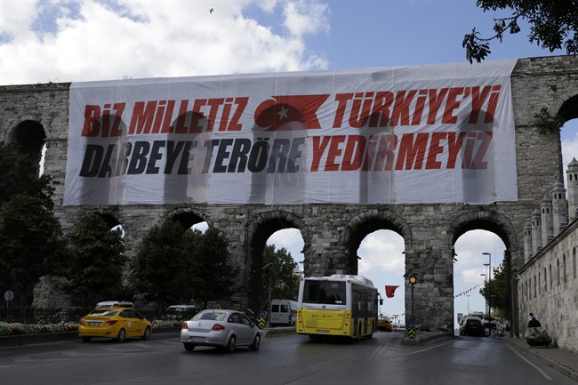 Vehicles pass the Valens Aqueduct with a banner reading ''We are the nation, we won't let Turkey fall to coups and terrorism'' in Istanbul, on Monday, Aug. 15, 2016.