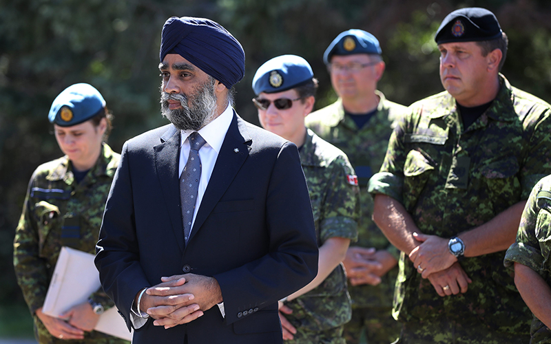 Defence Minister Harjit Sajjan stands with Canadian soldiers before an announcement at CFB Trenton in Trenton, Ont., on Aug. 29, 2016. 