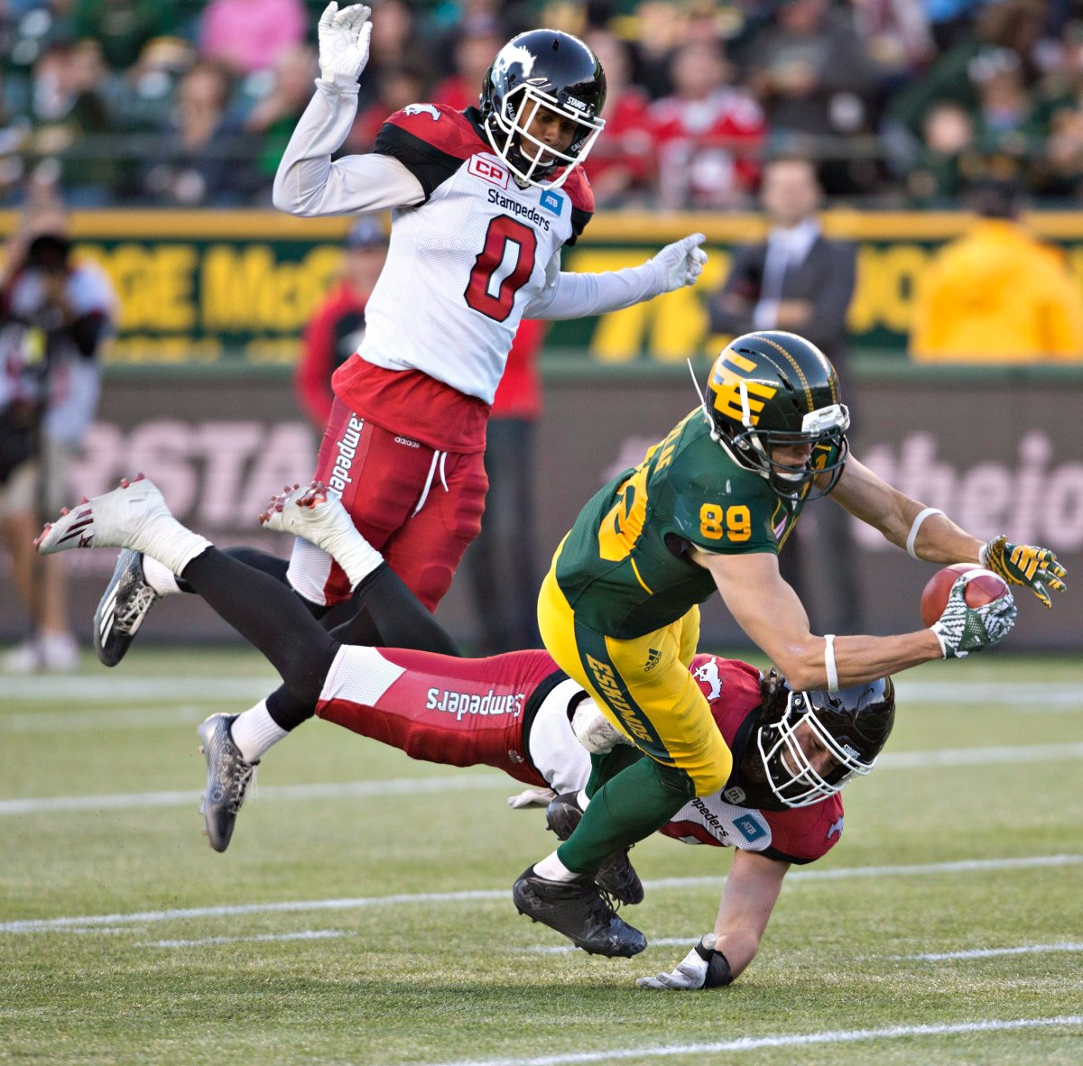 Calgary Stampeders Ciante Evans (0) and Alex Singleton (49) try to stop Edmonton Eskimos Chris Getzlaf (89) from making the catch during second half CFL action in Edmonton, Alta., on Saturday September 10, 2016. .