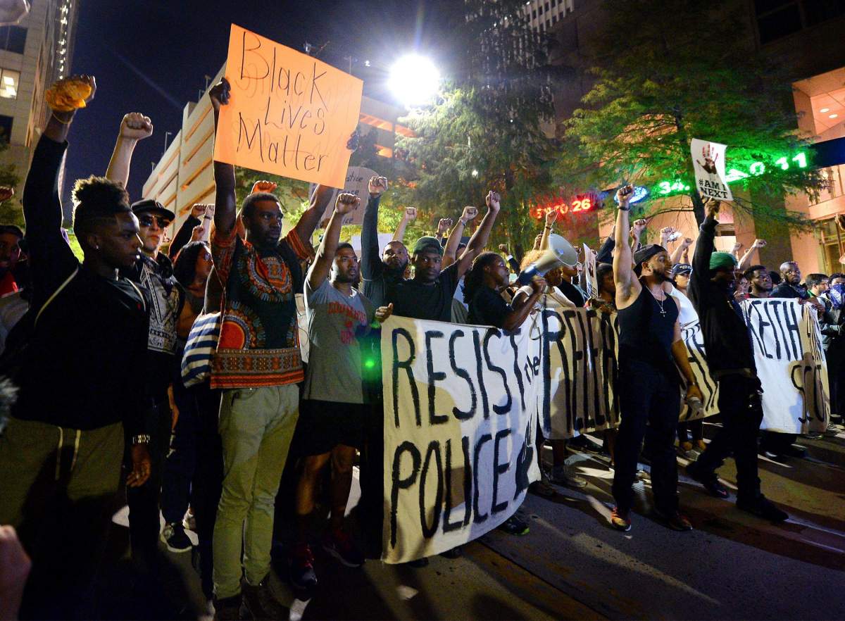 Protesters stand in unity as they prepare to march throughout the city to protest Tuesday's fatal police shooting of Keith Lamont Scott, in Charlotte, N.C., Friday, Sept. 23, 2016. 
