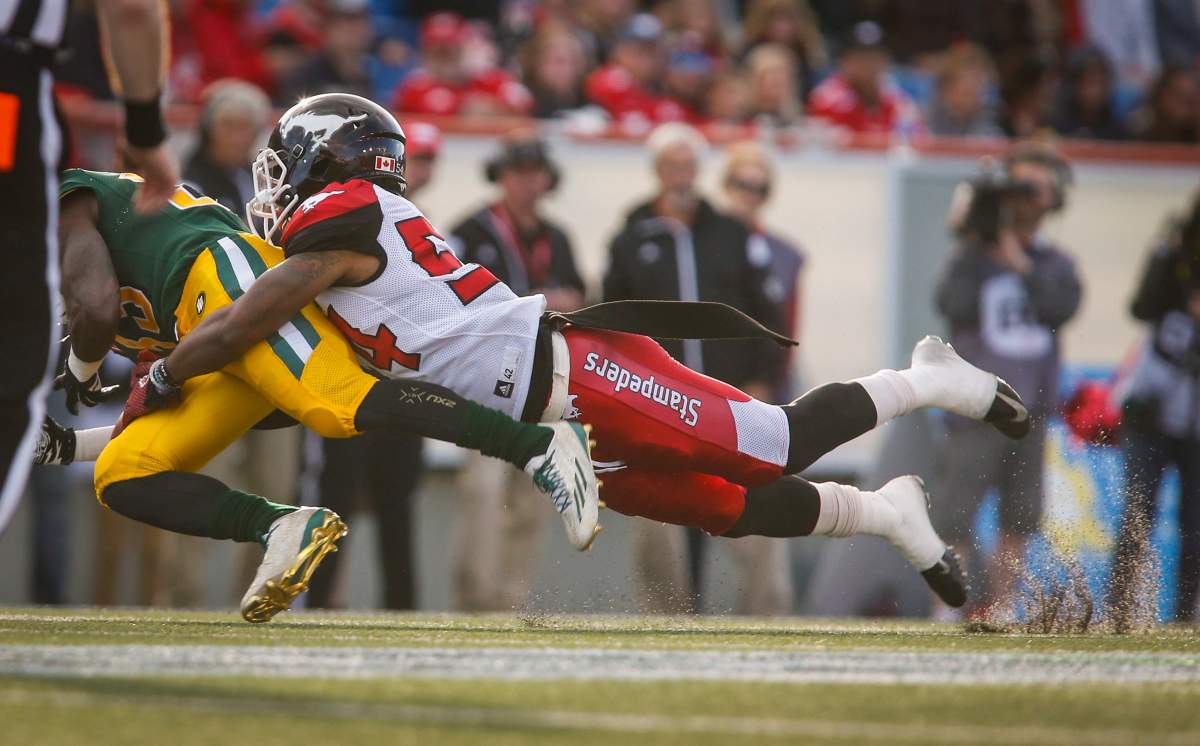 Edmonton Eskimos’ Shakir Bell, left, is hauled down by Calgary Stampeders’ Mylan Hicks during first half CFL pre-season football action in Calgary, Saturday, June 11, 2016.