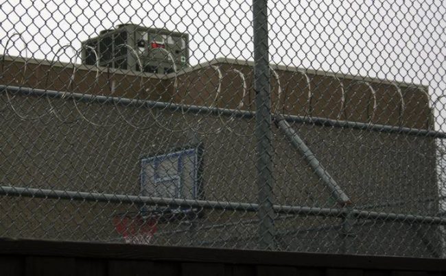 A basketball net can be glimpsed behind razor wire at the Toronto Immigration Holding Centre.