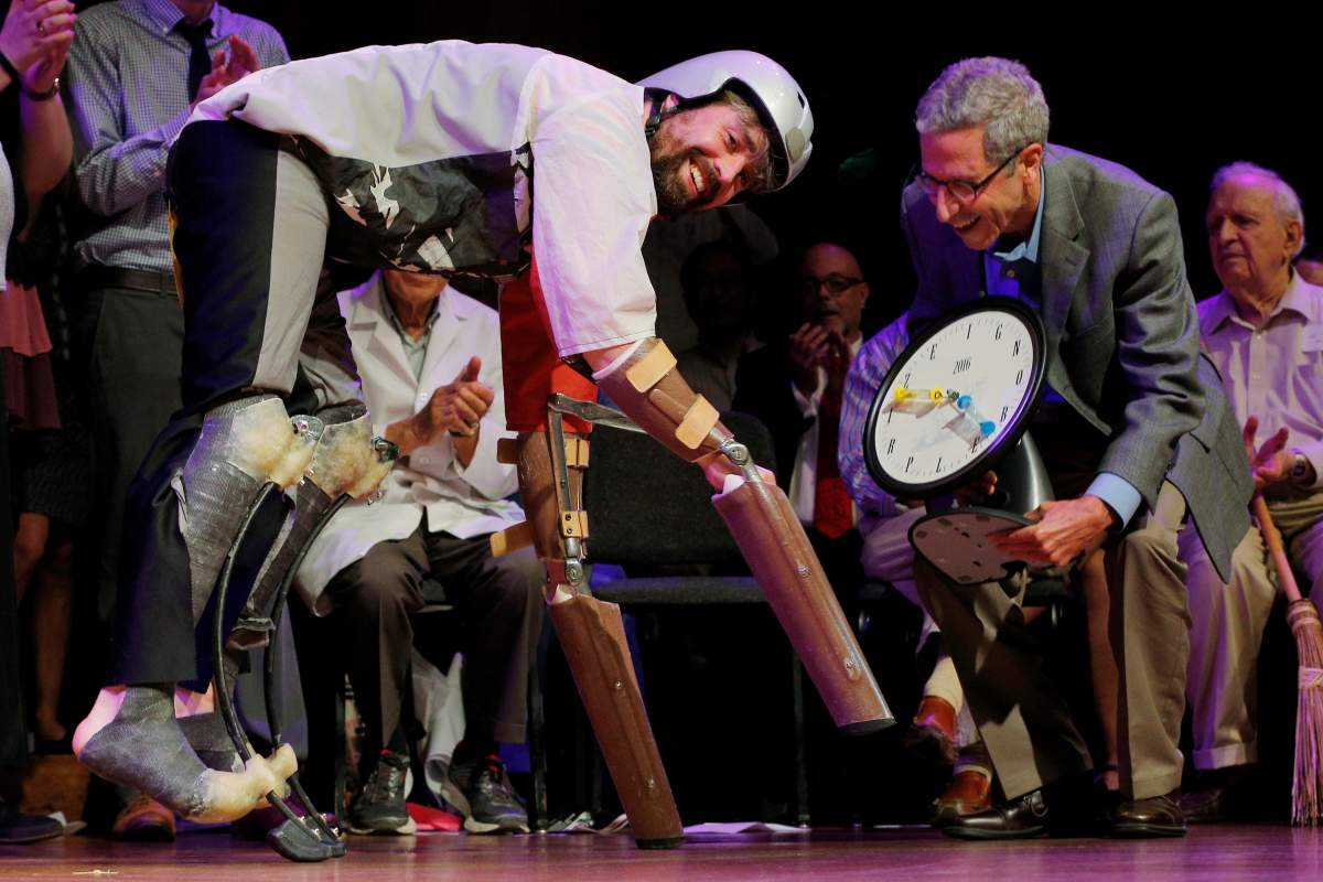 Nobel Laureate Eric Maskin (R) presents the 2016 Ig Nobel Prize in Biology to Thomas Thwaites of the United Kingdom for “creating prosthetic extension of his limbs that allowed him to move in the manner of, and spend time roaming the hills in the company of, goats” during the 26th First Annual Ig Nobel Prize ceremony at Harvard University in Cambridge, Massachusetts, U.S. September 22, 2016.
