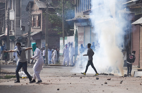 Kashmiri Muslim protesters throw stones at Indian government forces as they are being tear gassed amid a curfew during the Eid al-Adha festival on September 13, 2016 in Srinagar, the summer capital of Indian administered Kashmir, India. (Photo by Yawar Nazir/Getty Images).