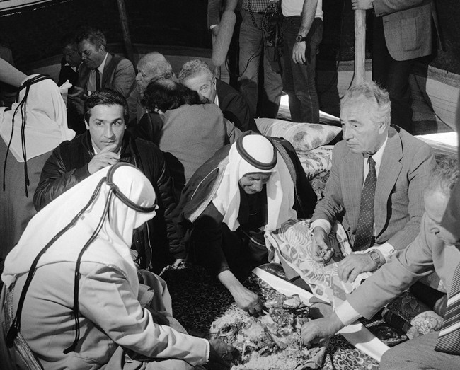 FILE - In this Tuesday, Jan. 29, 1985, file photo, Israel's Prime Minister Shimon Peres, right, eats with his hands as is the Bedouin custom during a feast he was invited too by Sheik Ali Abu Rubeia, second right; in the Negev desert in K'Seifa. Peres, a former Israeli president and prime minister, whose life story mirrored that of the Jewish state and who was celebrated around the world as a Nobel prize-winning visionary who pushed his country toward peace, has died, the Israeli news website YNet reported early Wednesday, Sept. 28, 2016. He was 93.