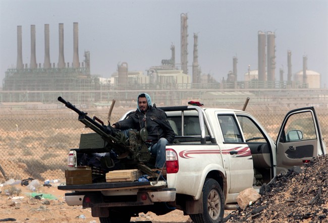 A Libyan anti-government rebel sits with an anti-aircraft weapon in front an oil refinery in Ras Lanouf, eastern Libya, March 2011.