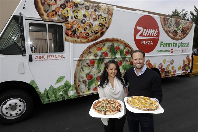 In this Monday, Aug. 29, 2016 photo, CEO and co-founder Julia Collins, left, and co-founder Alex Garden pose for a photo in front of one of the company's delivery trucks at Zume Pizza in Mountain View, Calif. The startup, which began delivery in April, is using intelligent machines to grab a slice of the multi-billion-dollar pizza delivery market. Zume is one of a growing number of food-tech firms seeking to disrupt the restaurant industry with software and robots that let them cut costs, speed production and improve worker safety.