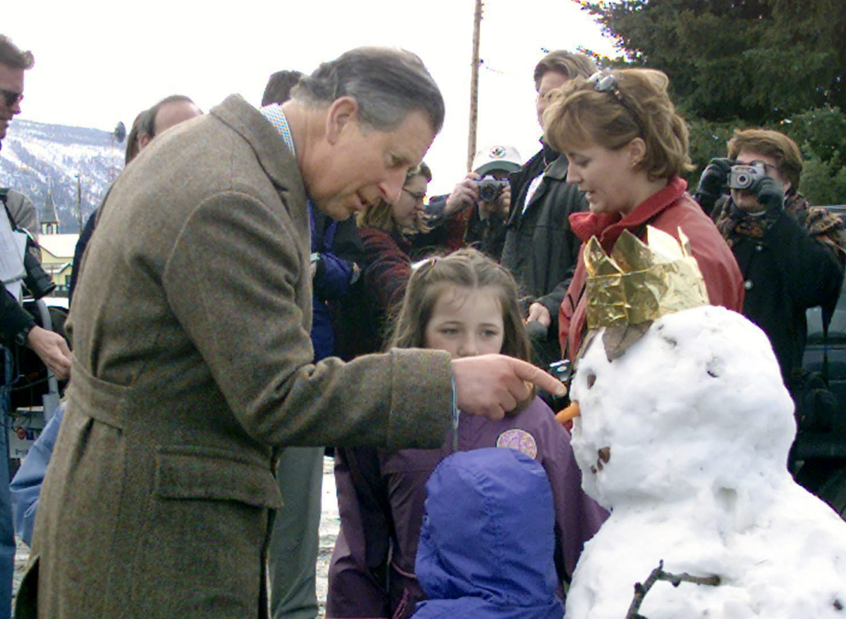 Prince Charles, the Prince of Wales, stops to chat with children who built a snowman for him, complete with a crown during a visit to Mayo, Yukon, Sunday, April 29, 2001.