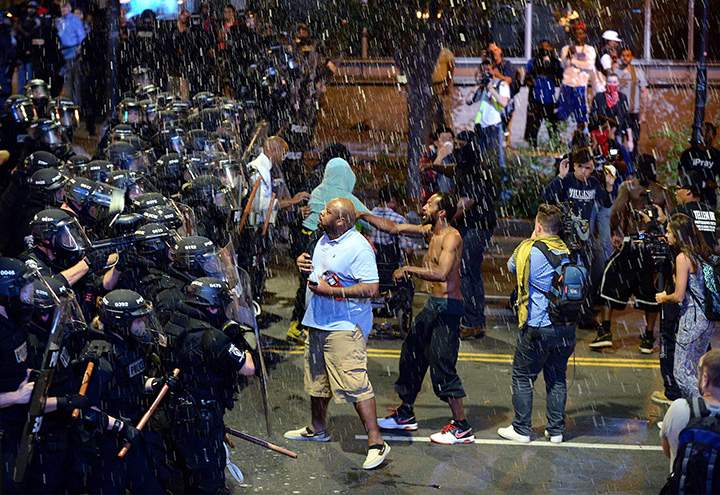 Debris falls upon Charlotte-Mecklenburg police officers and protesters as officers began to push demonstrators from the intersection near the Epicentre in Charlotte, N.C. Wednesday, Sept. 21, 2016.