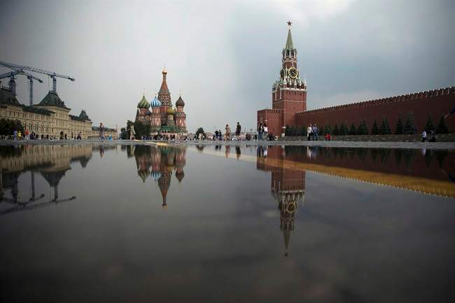 St. Bazil's Cathedral, center, and the Kremlin's Spasskaya Tower, right, are reflected in a puddle at the Red Square after a heavy rain in Moscow, Russia, Wednesday, July 27, 2016.