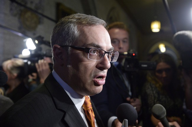 Treasury Board President Tony Clement fields questions in the foyer outside the House of Commons in Ottawa, Monday, May 11, 2015. 