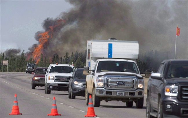 Evacuees drive past a fireball as a wildfire rips through the forest beside Highway 63, some 16 kilometres south of Fort McMurray, Alta. on Saturday, May 7, 2016. 