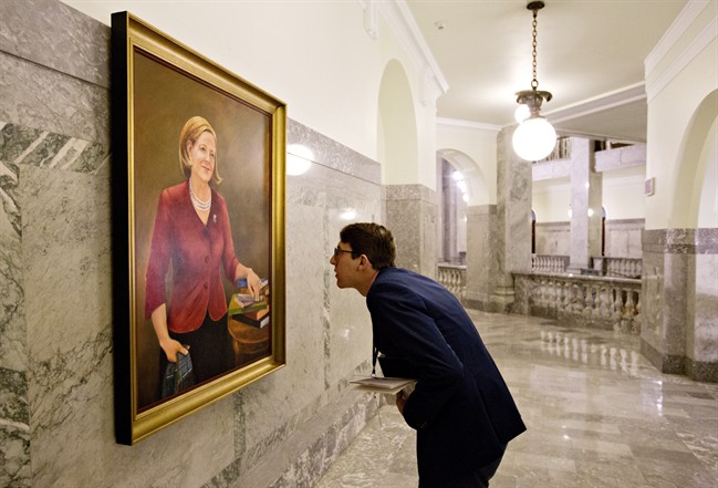 A government worker examines a painting of former Alberta Premier Alison Redford hanging in the Alberta Legislature amongst past premiers, in Edmonton on Thursday, September 8, 2016.