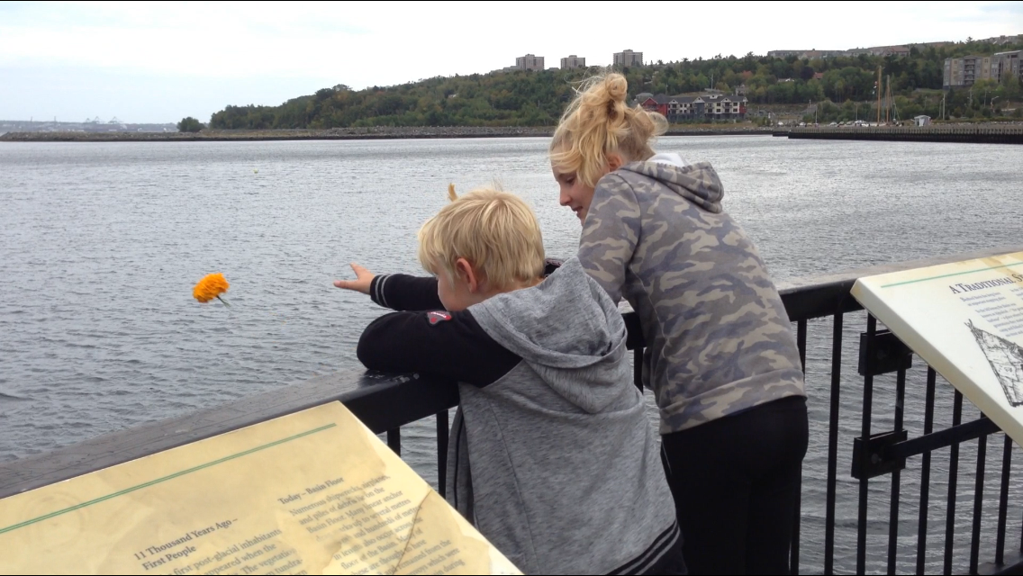 Grace Ferrall and her brother throw flowers into the Bedford Basin in honour of their missing cat, Jazzy.