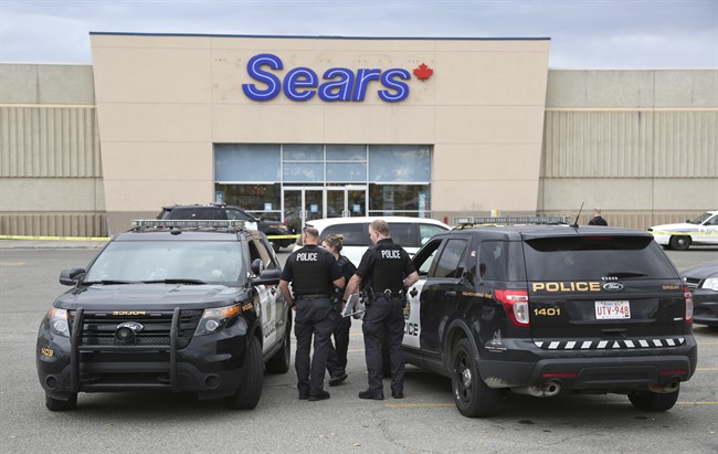 Police talk to one another outside the Sears store at the Marlborough Mall following an incident which left a police officer injured, in Calgary, Saturday, Sept. 17, 2016. 