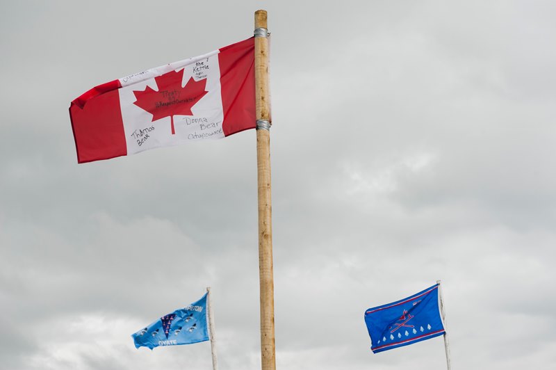Flags brought by Native American and Canadian First Nation tribes fly over an encampment where hundreds of protestors have gathered on the banks of the Cannon Ball River