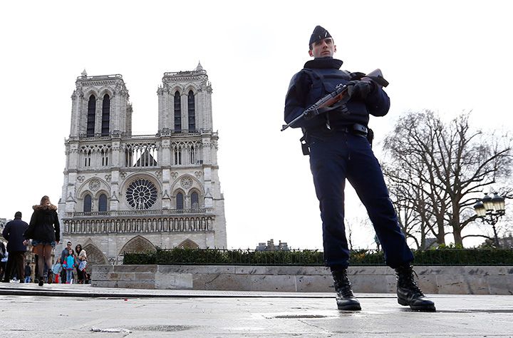 In this March 27, 2016 file photo, a French Police officer stands guard as worshipers arrive for the Easter mass at Notre Dame Cathedral, in Paris. 