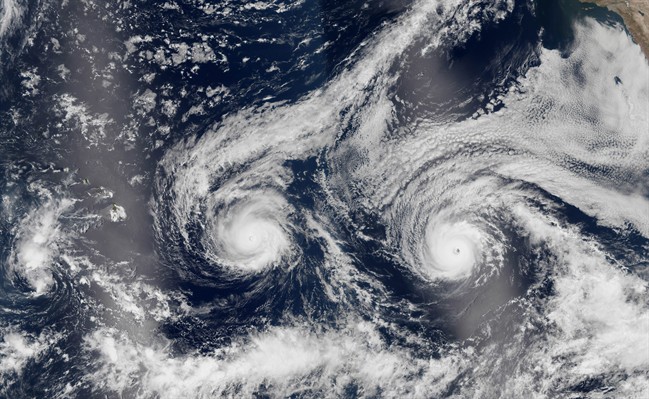 This satellite image taken Monday, Aug. 29, 2016 and released by NASA shows Hurricane Madeline, left, and Hurricane Lester over the Pacific Ocean in a composite built from two overpasses by the Visible Infrared Imaging Radiometer Suite on the Suomi NPP satellite. The National Weather Service issued a hurricane warning as the storm dubbed Madeline churned west Tuesday, Aug. 30, 2016, toward the island, urging residents to rush through preparations to protect themselves and their property and expect hurricane conditions within the next 36 hours. (NASA via AP).