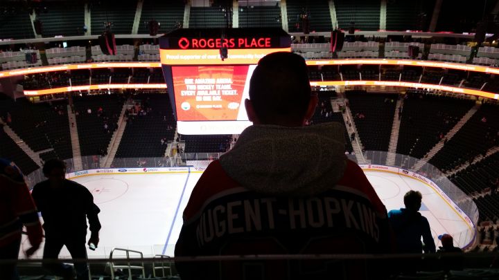 The view of the ice at Rogers Place from the Drink Rail seating in the upper bowl, with a person sitting in the row in front of the seats. 