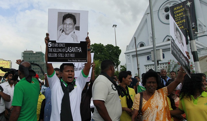 In this Jan. 28, 2014 file photo, a protester holds a portrait of Lasantha Wickrematunge, a journalist who was killed, during a protest in Colombo, Sri Lanka. A Sri Lankan court on Thursday gave permission to police to exhume the remains of the newspaper editor killed seven years ago for a fresh investigation.