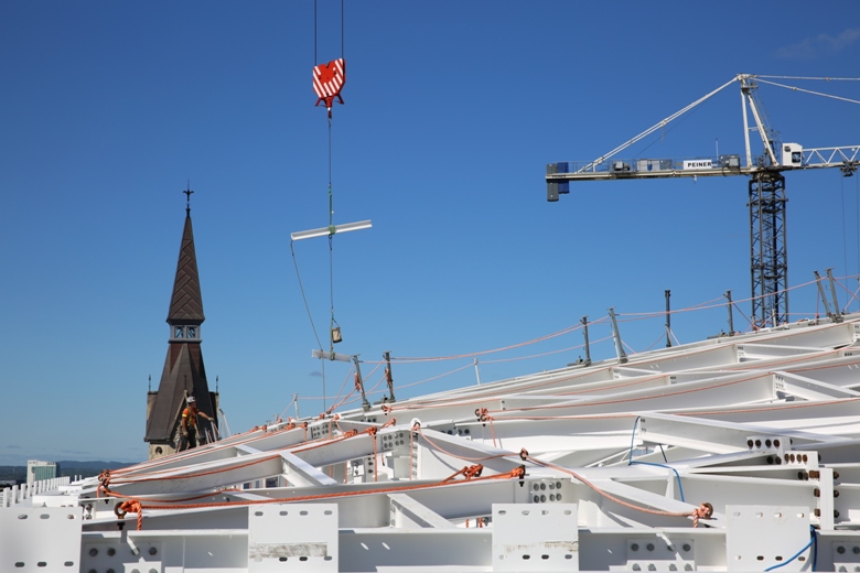 A view across the roof of Parliament Hill’s West Block as a crane delivers the next beam to be installed. The network of white steel beams will support a glass ceiling over the temporary House of Commons.