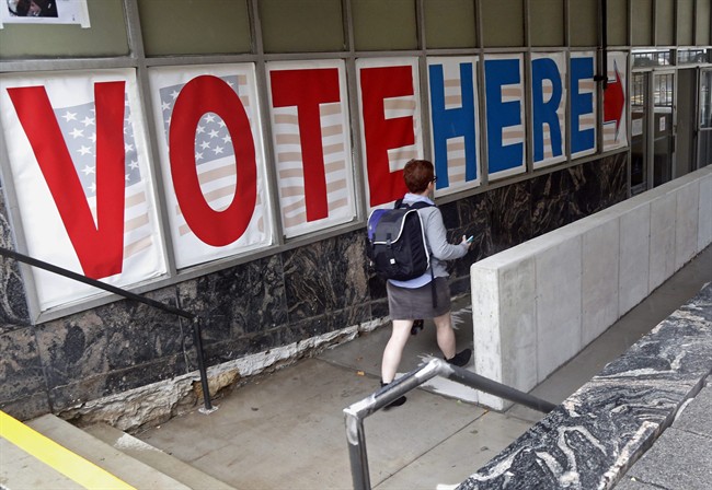 In this Sept. 23, 2016 file photo, a woman passes a large sign before voting in Minneapolis. Americans will vote for much more than a  president next Tuesday.