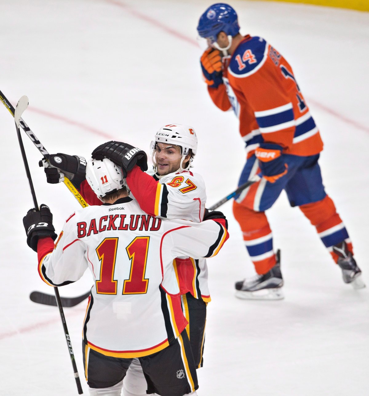Calgary Flames' Mikael Backlund (11) and Michael Frolik (67) celebrate a goal as Edmonton Oilers' Jordan Eberle (14) skates past during second period NHL action in Edmonton, Alta., on Wednesday October 12, 2016. 