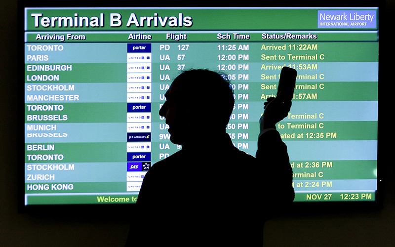 A person points to a screen of an airplane travel list while holding up a phone at Newark Liberty International Airport, in Newark, N.J. 