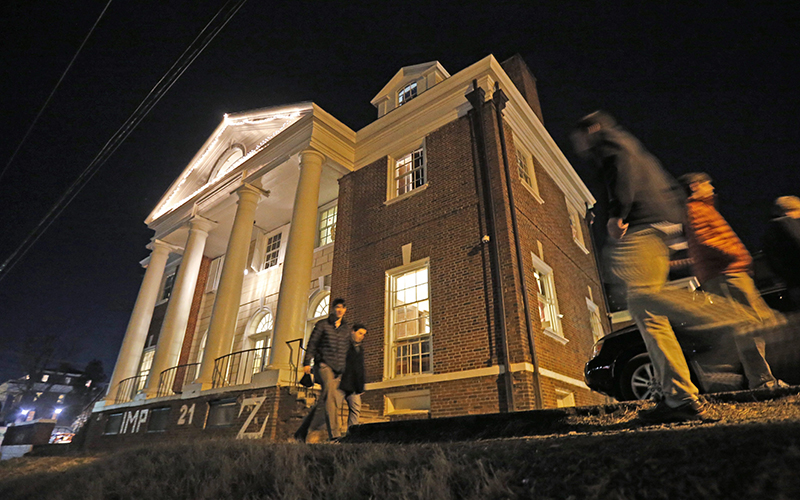 Students pass by the Phi Kappa Psi house at the University of Virginia in Charlottesville, Va. The house was depicted in a debunked Rolling Stone story as the site of a rape in September of 2012. 