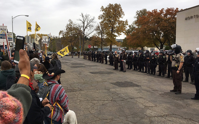 Police officers line up as a protest grows outside the Morton County Courthouse in Mandan, N.D., Monday, Oct. 17, 2016.  A judge dismissed a complaint Monday against Democracy Now journalist Amy Goodman, who reported on a clash between pipeline protesters and private security in September. 