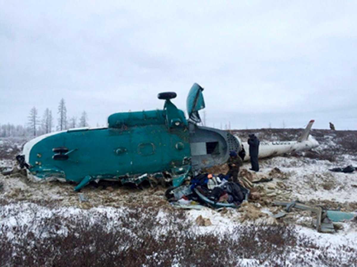 In this handout photo, made available by Russian Emergency Situations Ministry, Saturday, Oct. 22, 2016, a Mi-8 helicopter lies on the ground after it crashed about 45 kilometers (28 miles) northeast of Staryi Urengoi in Hassana, Russia. Russia's aviation agency says 19 people have died after a helicopter carrying oil workers crashed. 