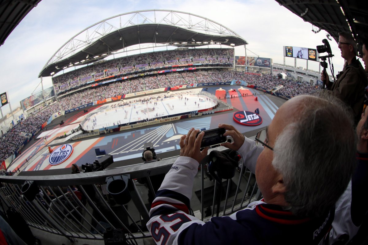 A Winnipeg Jets fan takes a photo of the opening festivities as the Winnipeg Jets take on the Edmonton Oilers at the NHL Heritage Classic Alumni Game in Winnipeg on Saturday.