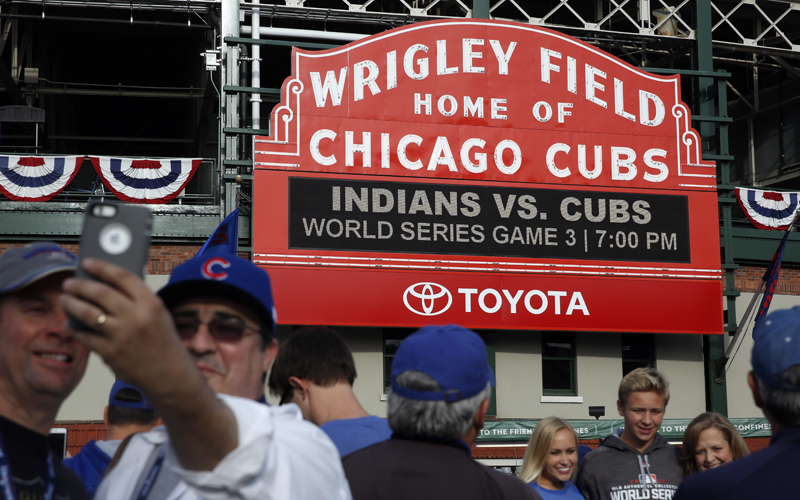 Fans take pictures in front of the Wrigley Field marquee before Game 3 of the Major League Baseball World Series between the Chicago Cubs and the Cleveland Indians, Friday, Oct. 28, 2016, in Chicago.