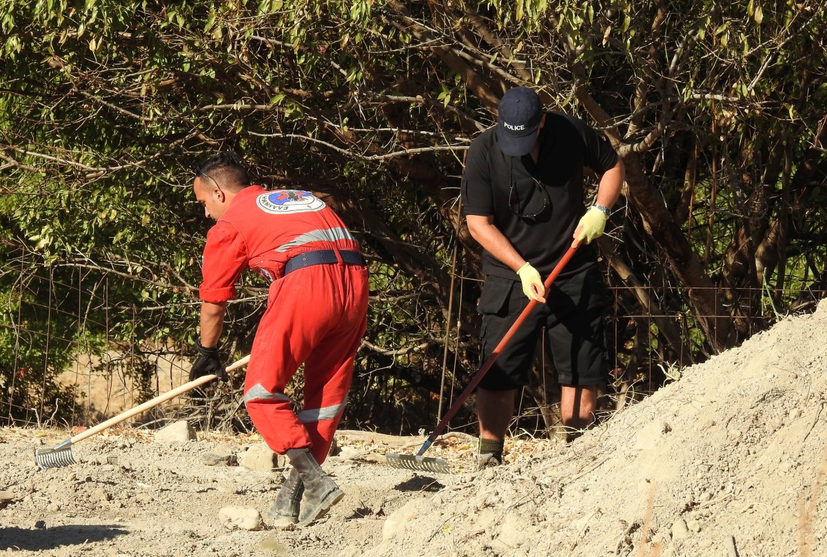 A South Yorkshire police officer (R) and a member of the Greek rescue service (in red uniform) investigate the ground while excavating a site for Ben Needham, a 21 month old British toddler who went missing in 1991, on the island of Kos, Greece, September 28, 2016. 
