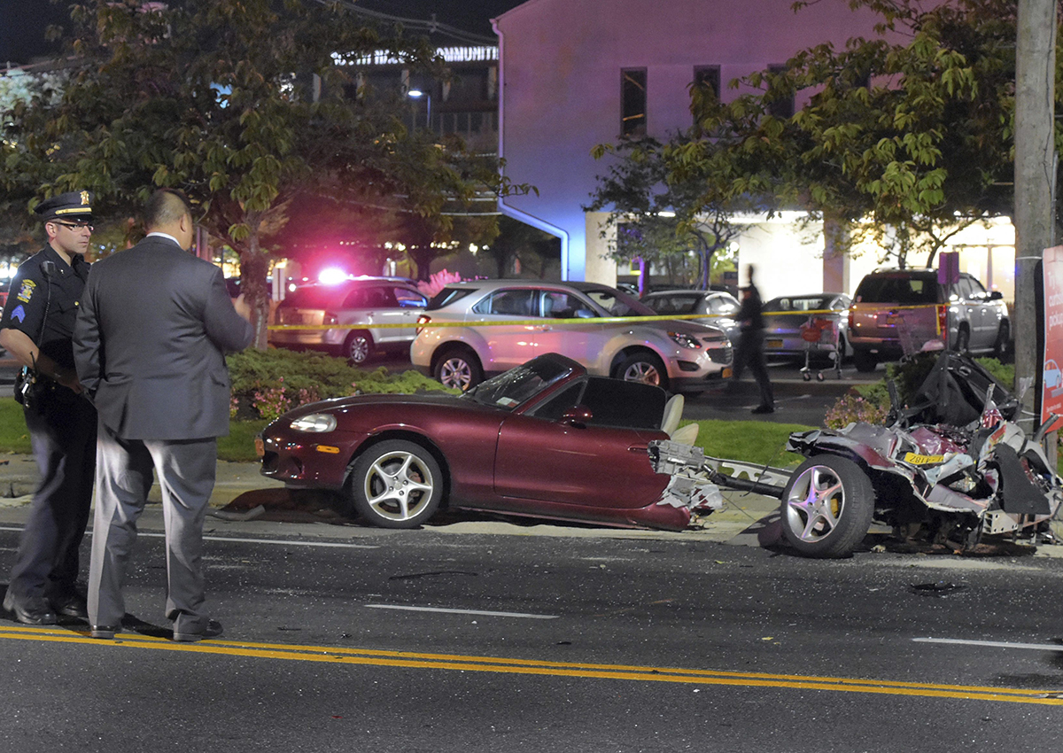 Police survey the wreckage of a Mazda Miata that was split in half after a collision with a Mercedes-Benz in Rockville Centre, on New York's Long Island, Friday Oct. 14, 2016.
